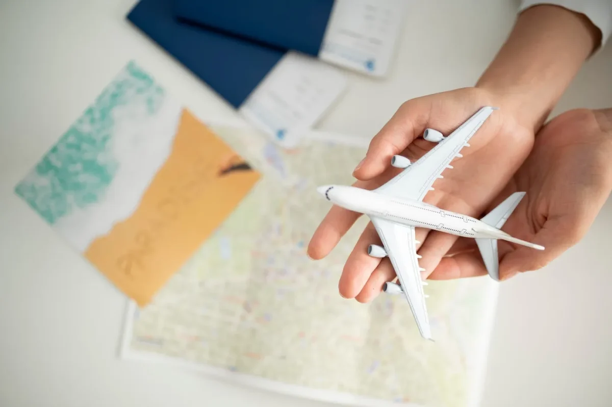 dicas-para-quem-vai-viajar-de-aviao-pela-primeira-vez-maos-masculinas-segurando-aviao-em-miniatura-sobre-uma-mesa-com-mapas-de-viagens
