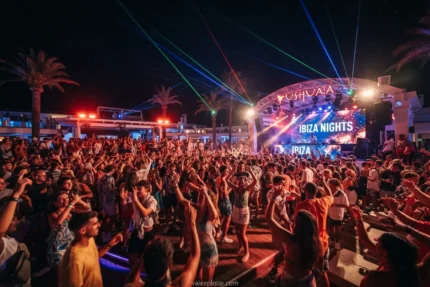 As melhores baladas em Ibiza com pessoas dançando ao ar livre sob luzes coloridas